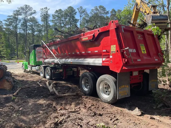 Red dump truck being loaded with debris for haul-off